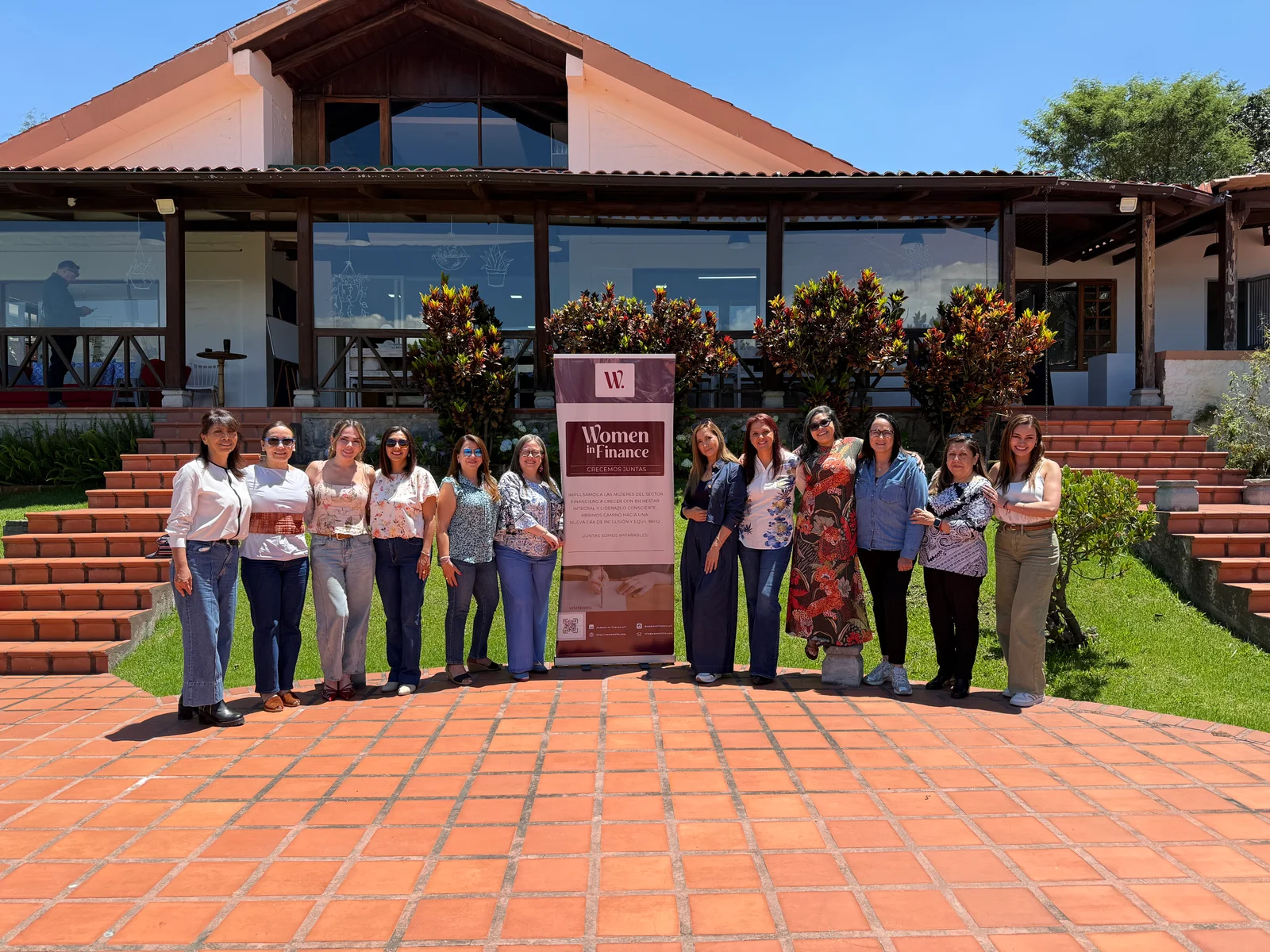 Grupo de la comunidad WIF junto a su banner en una terraza exterior.