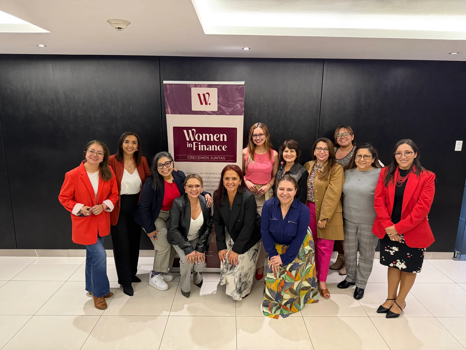Grupo de participantes junto al banner de Women in Finance.