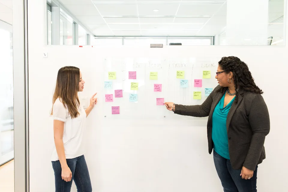 Dos profesionales anotan ideas frente a un tablero.